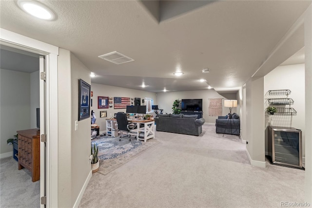 carpeted office space with baseboards, beverage cooler, visible vents, and a textured ceiling