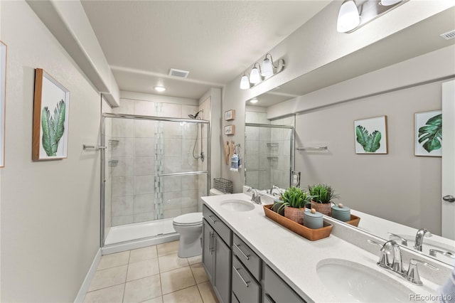 bathroom featuring toilet, a stall shower, a sink, and tile patterned floors