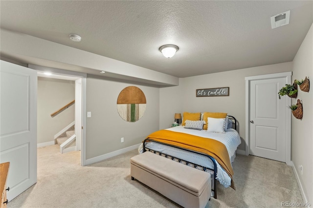 bedroom with a textured ceiling, baseboards, visible vents, and light colored carpet