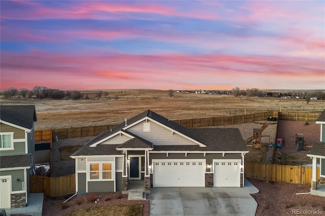 view of front of property with stone siding, concrete driveway, fence, and an attached garage