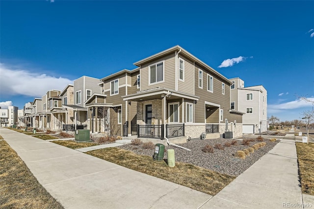 view of side of property with a porch, a residential view, stone siding, and central AC