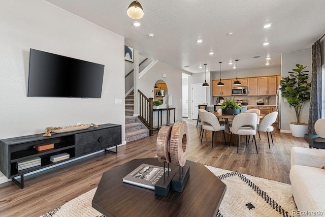 2118 Wagon Wheel Aly, Brighton, CO 80601 - living area featuring light wood finished floors, stairs, arched walkways, and recessed lighting