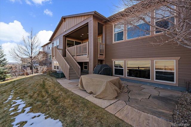 snow covered property with stairs, board and batten siding, and a yard