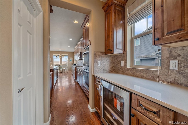 kitchen with an inviting chandelier, hanging light fixtures, wine cooler, dark hardwood / wood-style flooring, and decorative backsplash