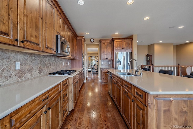 kitchen featuring tasteful backsplash, sink, hardwood / wood-style flooring, a kitchen island with sink, and stainless steel appliances