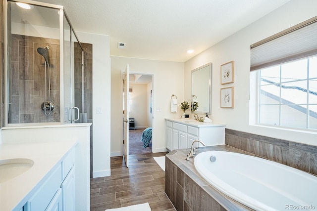 9607 Williamsburg St, Littleton, CO 80125 - ensuite bathroom with two vanities, a garden tub, a stall shower, wood finished floors, and recessed lighting
