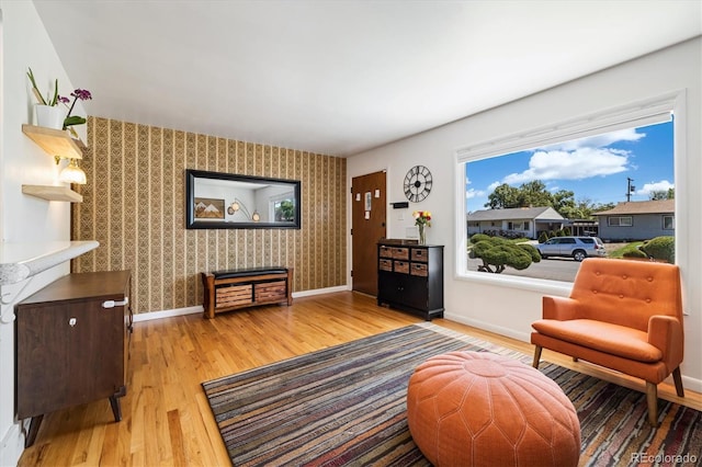 1211 S Zuni St, Denver, CO 80223 - living area featuring wood finished floors, wallpapered walls, baseboards, and an accent wall