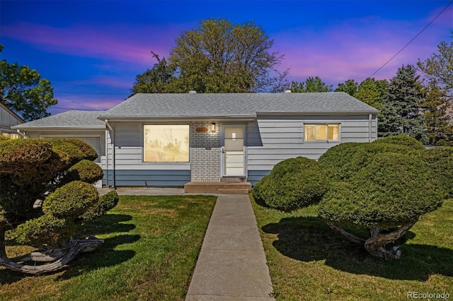 1211 S Zuni St, Denver, CO 80223 - view of front of home with a yard, an attached garage, and roof with shingles
