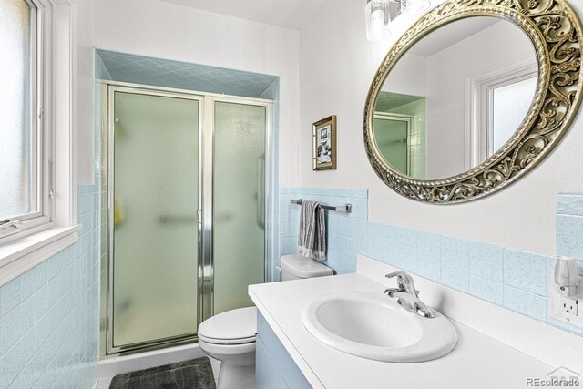 1903 Northmoor Ter, Pueblo, CO 81008 - bathroom featuring tile walls, toilet, a stall shower, vanity, and tile patterned flooring