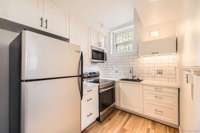 kitchen with appliances with stainless steel finishes, a sink, light countertops, decorative backsplash, and white cabinets