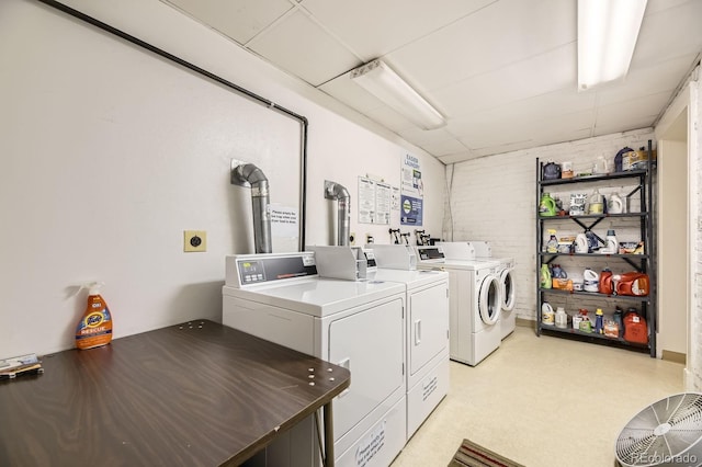 communal laundry room featuring washer and clothes dryer and brick wall