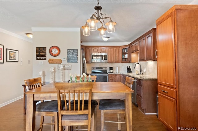 dining area with dark hardwood / wood-style flooring, a textured ceiling, crown molding, sink, and a notable chandelier