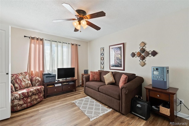 living room featuring ceiling fan, a textured ceiling, and light hardwood / wood-style flooring