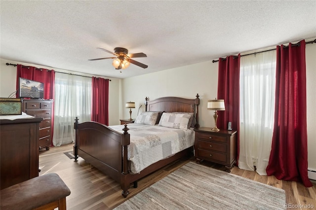 bedroom featuring ceiling fan, a textured ceiling, and light wood-type flooring