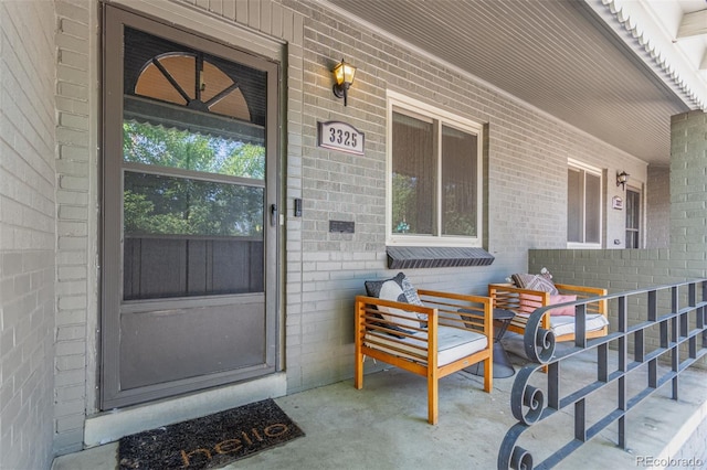 view of exterior entry with covered porch and brick siding