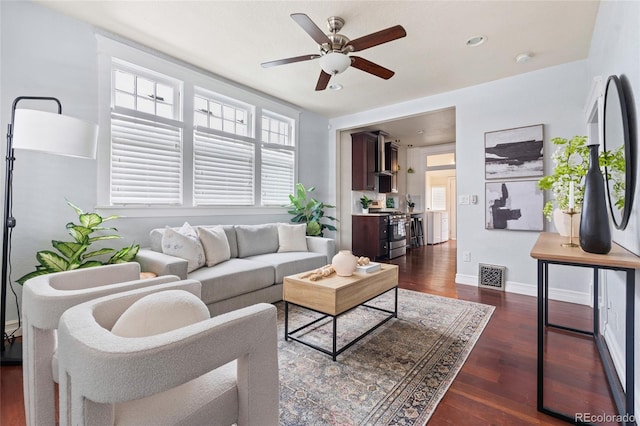 living area with dark wood-style floors, baseboards, visible vents, and a ceiling fan