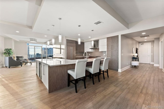 2001 Lincoln St Unit 2524, Denver, CO 80202 - kitchen featuring wall chimney exhaust hood, modern cabinets, light wood finished floors, light countertops, and recessed lighting