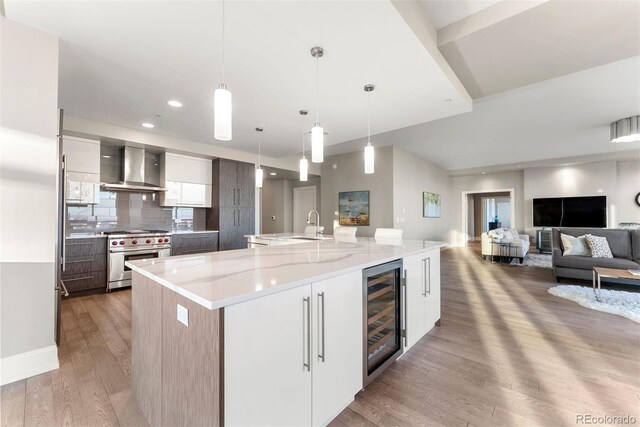 2001 Lincoln St Unit 2524, Denver, CO 80202 - kitchen featuring beverage cooler, high end stainless steel range, modern cabinets, wall chimney range hood, and light wood-style flooring