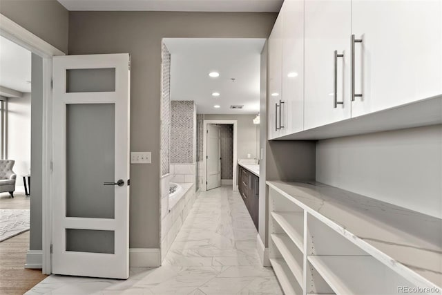 2001 Lincoln St Unit 2524, Denver, CO 80202 - full bathroom with marble look tiles, vanity, recessed lighting, a garden tub, and baseboards