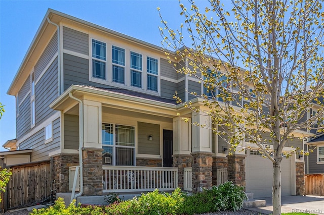 view of front of property featuring concrete driveway, stone siding, a porch, and fence