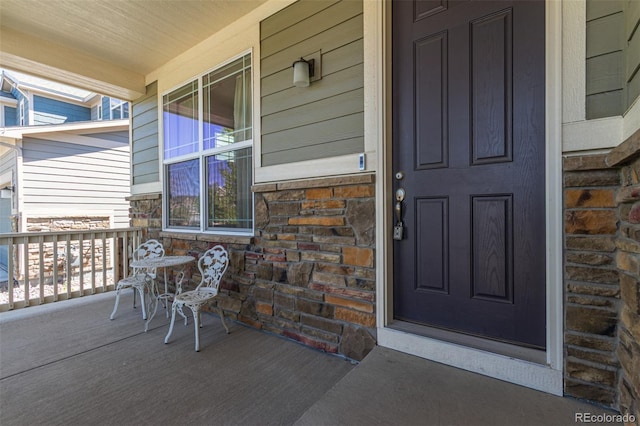 doorway to property with stone siding and a porch