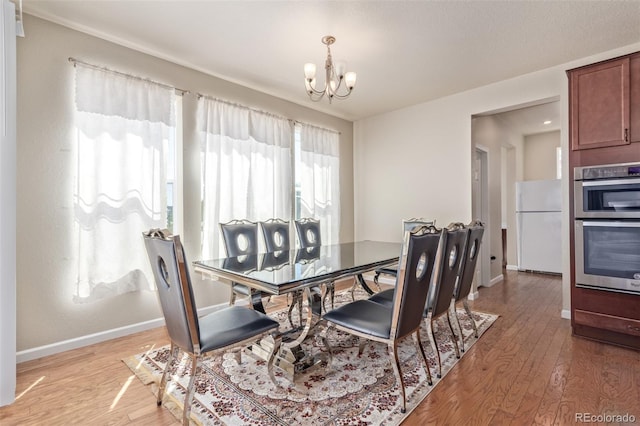 dining space featuring baseboards, light wood-style flooring, and a notable chandelier