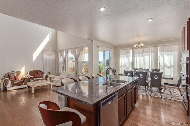 kitchen featuring a sink, stainless steel appliances, dark wood-type flooring, and a breakfast bar