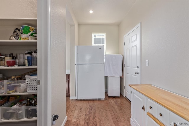 kitchen with freestanding refrigerator, light wood-style floors, white cabinetry, and wood counters