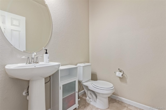 bathroom with toilet, baseboards, and tile patterned floors