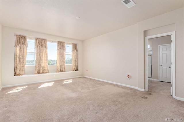 empty room featuring baseboards, visible vents, and light colored carpet