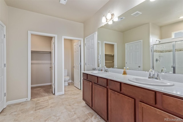 bathroom with a stall shower, toilet, a sink, and visible vents