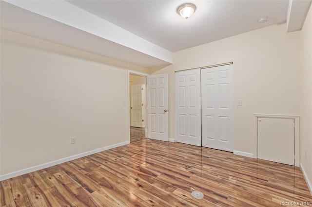 unfurnished bedroom featuring a closet, wood finished floors, and baseboards