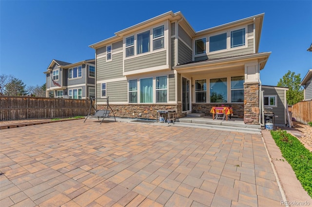back of house with stone siding, a patio, and fence private yard