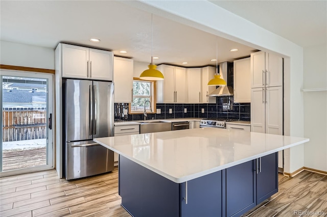 kitchen featuring wall chimney range hood, pendant lighting, appliances with stainless steel finishes, and white cabinetry