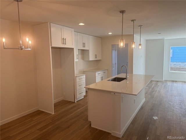 kitchen featuring an island with sink, a sink, white cabinetry, and dark wood-style flooring