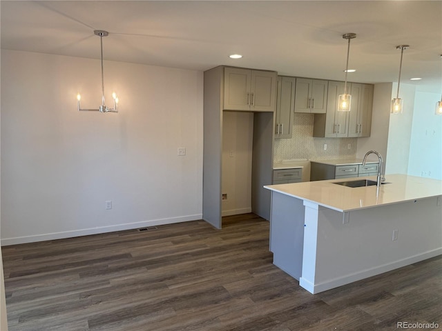 kitchen with baseboards, dark wood-style flooring, a sink, gray cabinetry, and backsplash