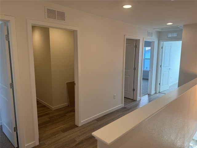 hallway with dark wood-style floors, baseboards, visible vents, and recessed lighting