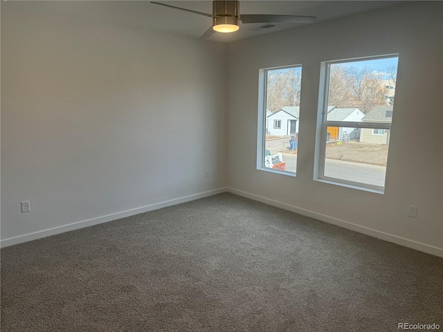 carpeted spare room with a ceiling fan, visible vents, and baseboards