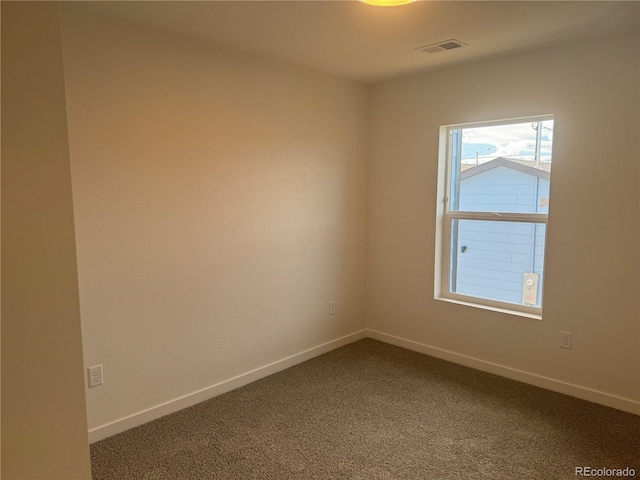 unfurnished room featuring dark colored carpet, visible vents, and baseboards