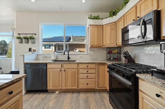 kitchen with light stone countertops, sink, light wood-type flooring, and black appliances