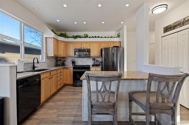 kitchen featuring sink, tasteful backsplash, black appliances, light stone countertops, and dark hardwood / wood-style flooring