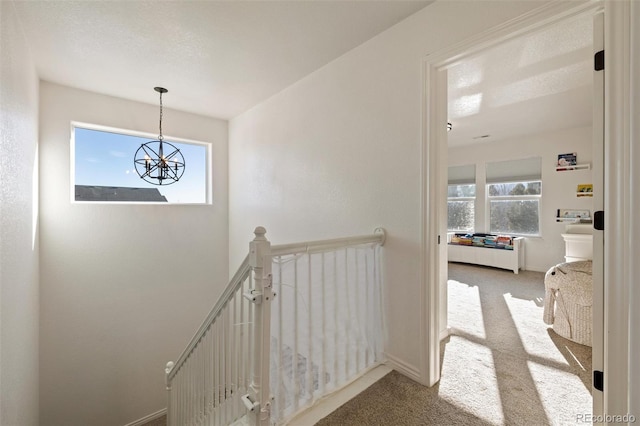 corridor featuring an inviting chandelier and light carpet