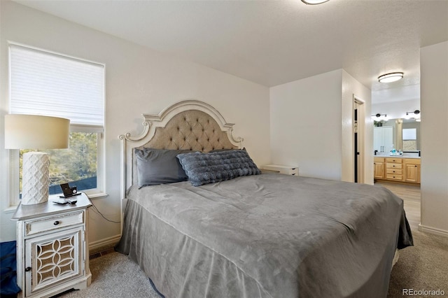 carpeted bedroom featuring ensuite bath