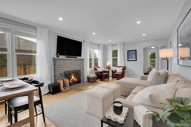 2212 Ingalls St, Edgewater, CO 80214 - living room featuring a stone fireplace, light wood-style flooring, recessed lighting, arched walkways, and ornamental molding