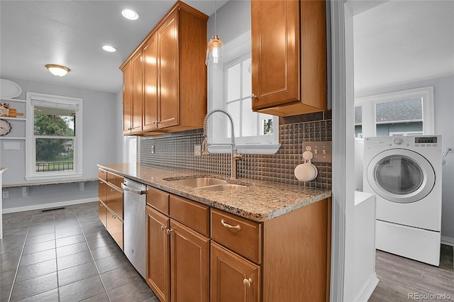 2212 Ingalls St, Edgewater, CO 80214 - kitchen with washer / dryer, stainless steel dishwasher, decorative backsplash, brown cabinets, and recessed lighting