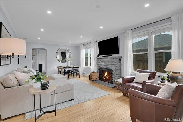 2212 Ingalls St, Edgewater, CO 80214 - living room featuring arched walkways, a fireplace, recessed lighting, light wood-style flooring, and crown molding