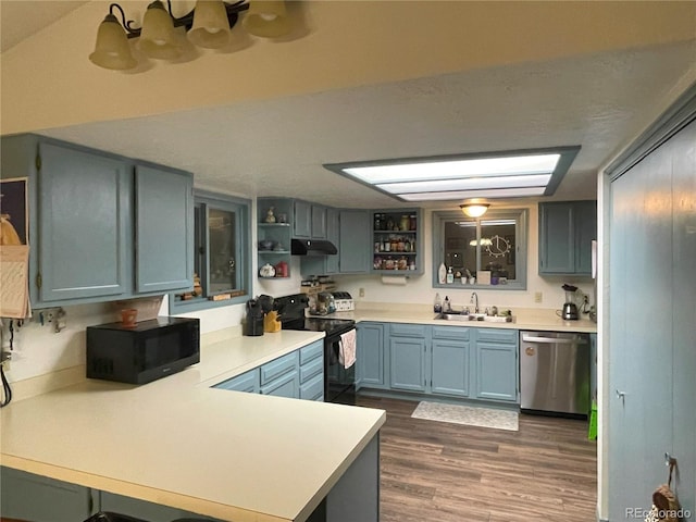 kitchen featuring open shelves, light countertops, a sink, a peninsula, and black appliances