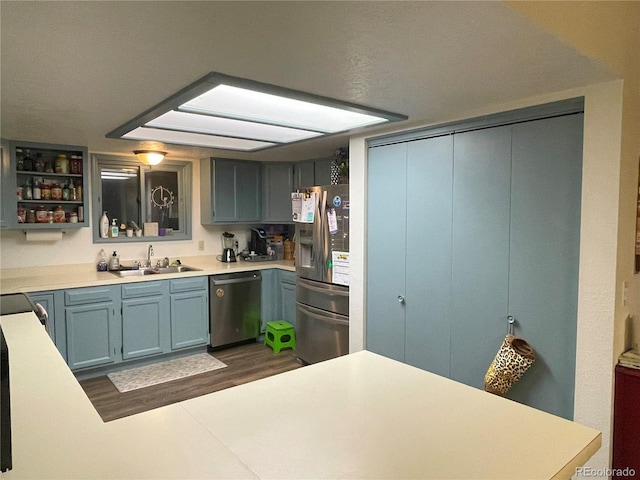 kitchen featuring stainless steel appliances, light countertops, a sink, and open shelves