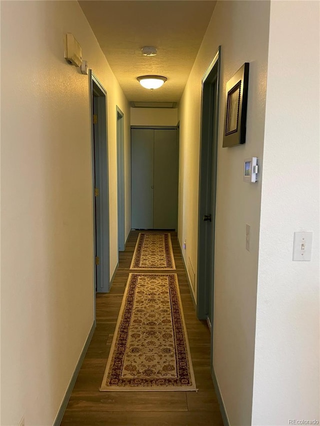 corridor with baseboards and wood finished floors