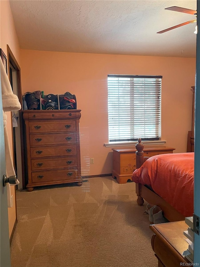 carpeted bedroom featuring ceiling fan and a textured ceiling